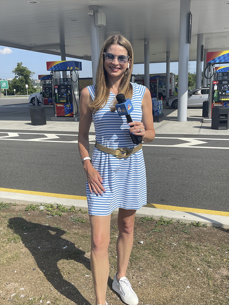 Jen anchoring in the field at a Raceway gas station, in fun sunglasses, a blue, horizontal striped sleeveless mini dress and sneakers.
